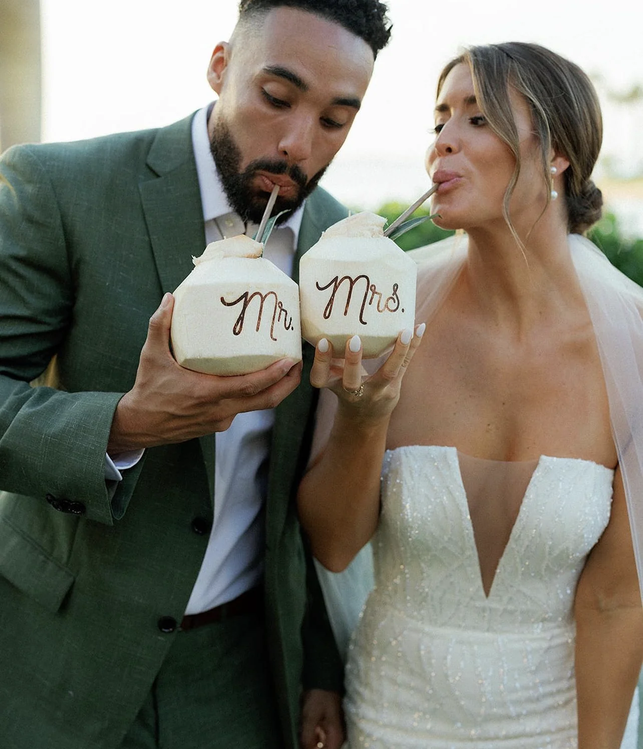 Bride and groom drinking from personalized coconuts