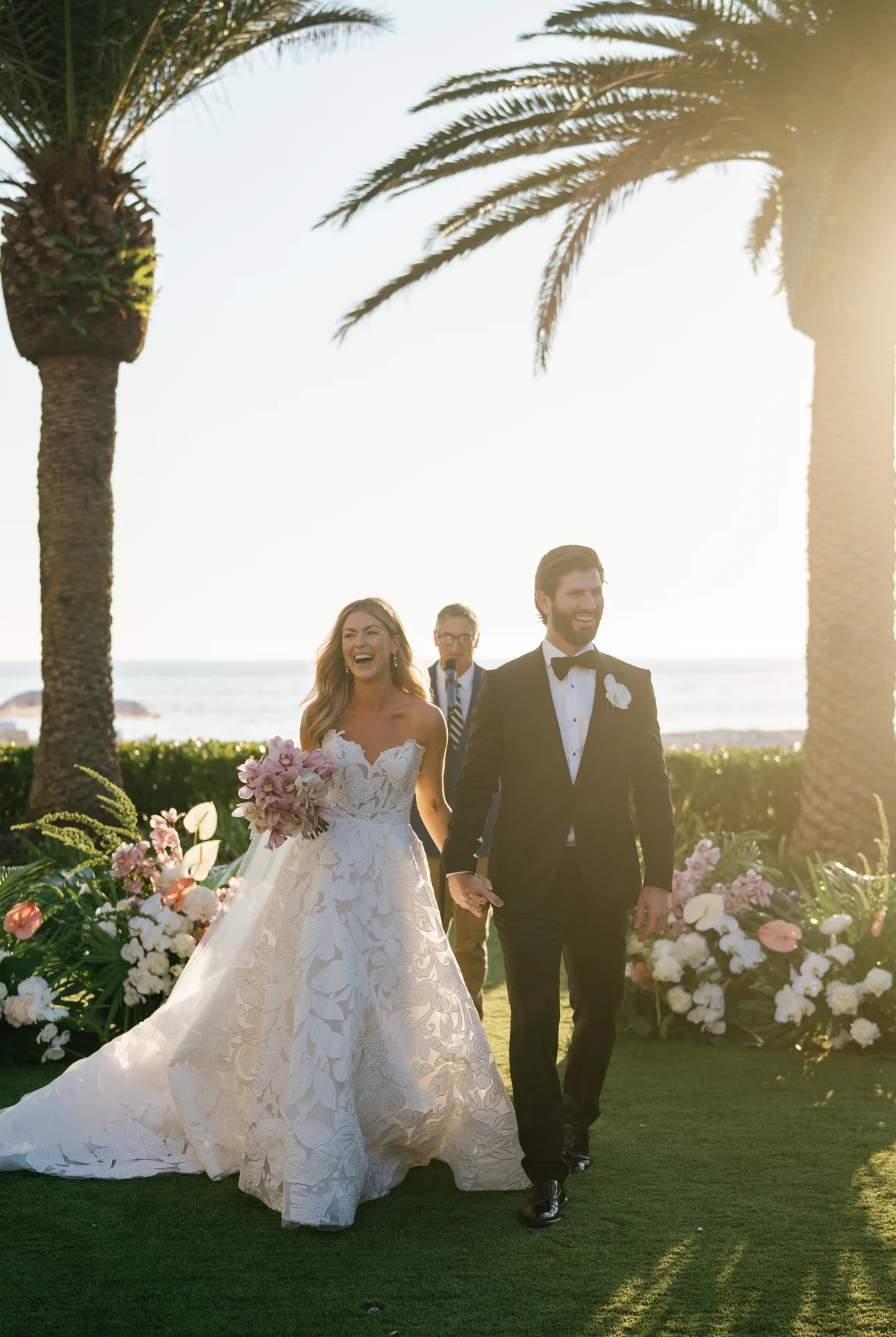 Bride and groom walking from their palm-lined ceremony
