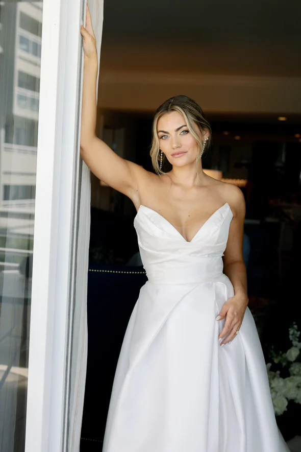 Bride in her wedding dress beside a bright window